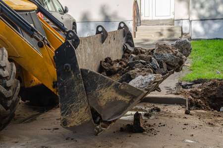 A large bulldozer bucket filled with earth and pieces of asphalt. Construction machines and...