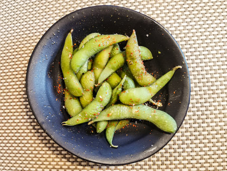 Edamame beans in salt and spices. Popular Russian snack of green beans in a black round bowl on the...