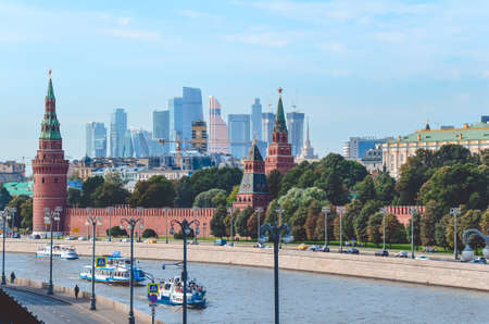 View of Moscow Kremlin and Kremlin wall, the Moscow River with passenger water transport, against the backdrop of skyscraper quarter. Mixing of eras. Main sights of Russia. Toned image with soft focusのeditorial素材