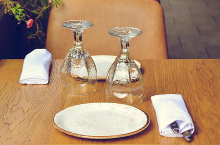Table on the veranda of the restaurant, served for two: two inverted glasses, napkins and cutlery on...