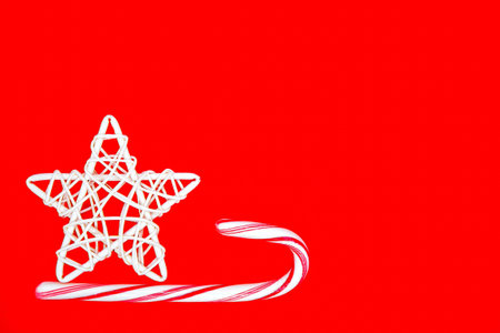 Red christmas background with white straw star and and striped candy cane. Christmas mood, gifts and...