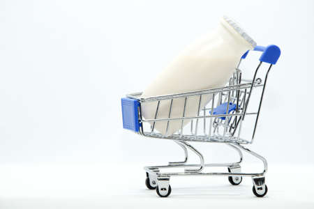 Natural yogurt with probiotics and Lactobacillus in small plastic bottles in metal supermarket trolley on white background. Healthy diet food, dairy products, go grocery shoppingの写真素材