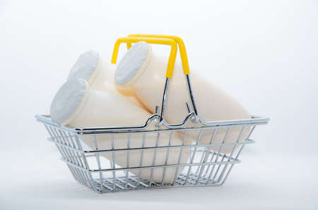 Natural yogurt with probiotics and Lactobacillus in small plastic bottles in metal shopping basket on white background. Healthy diet food, dairy products, go grocery shoppingの写真素材