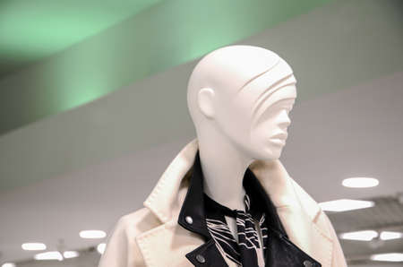 Female mannequin in elegant coat in the sales area of a women's clothing retail store. Woman doll in a shop window. Shopping, beauty or feminine concept.の写真素材