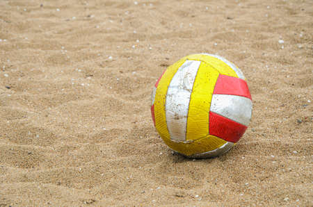 Shabby dirty volleyball on the sand beach. Attribute of beach volleyball, sports games on the coast. Space for text.の写真素材