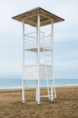 Empty lifeguard tower and red storm flag on the beach on a cloudy day. Security on public and private beaches. Vertical imageのeditorial素材