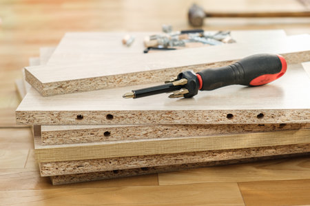Screwdriver with removable nozzles for assembling furniture on parts of cabinet furniture made of laminated chipboard background. Self-assembly of cabinet furniture.の写真素材