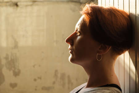Artistic portrait of a red-haired woman in profile. Backlit portrait of a woman. Close-up of a pensive woman.の写真素材