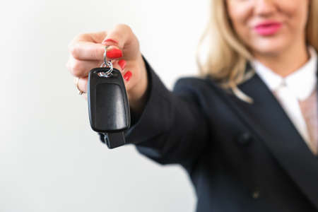 Employee of a car sales company hand over car key to client. Close-up of a car key. Car purchase symbol, rental, leasing. Mock up copy space.の写真素材