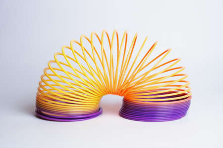 Popular plastic Slinky toy on a white background. A toy in the form of a long multi-colored flexible spring. Antistress toys, development of fine motor skills in children.のeditorial素材