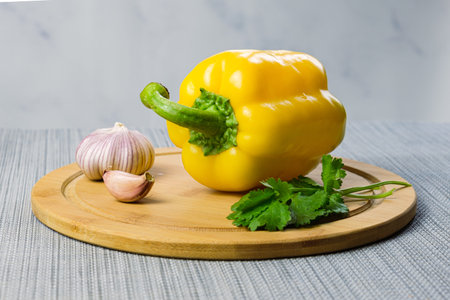 Yellow bell peppers, garlic and cilantro on a wooden cutting board. Vegetables ready for cooking....