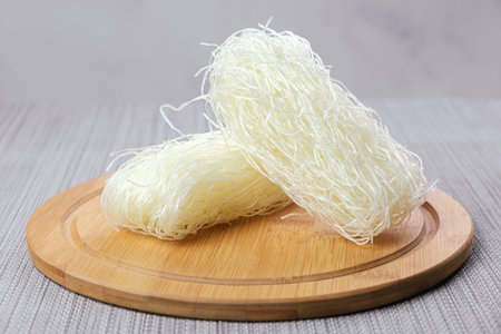 Two servings of dry funchose on a wooden cutting board. Ready-to-cook Chinese glass noodles....
