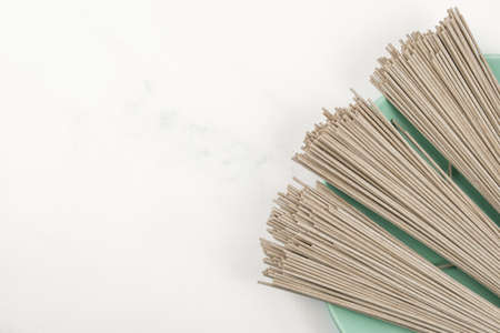 Dry Soba buckwheat noodles on a plate on a light marble top. Banner about traditional Japanese food, Asian food and healthy eating. Culinary template for adding text.の写真素材