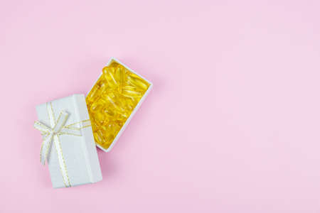 Fish Gelatin Softgels Omega-3 in a small white gift box. Healthy gifts concept. Festive background about a healthy lifestyle. Space to add text.の写真素材