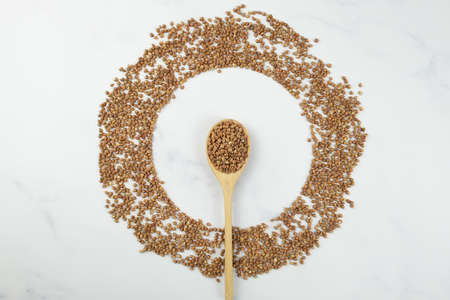 Buckwheat groats laid out in a circle. In the center of the circle is a wooden spoon with buckwheat. Creative culinary concept. Selective focus.の写真素材