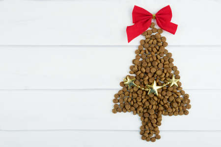Dry dog food Christmas tree with red bow on top and garland. Christmas pet supplies concept, New year and Christmas celebration. Top view, space to insert text.の写真素材