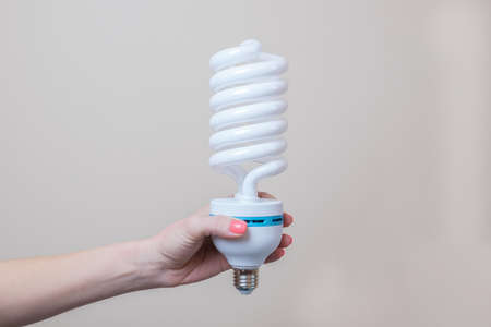 A female hand holds a large energy-saving lamp. The concept of energy saving, eco-friendly lifestyle. Use of economical lighting lamps.の写真素材