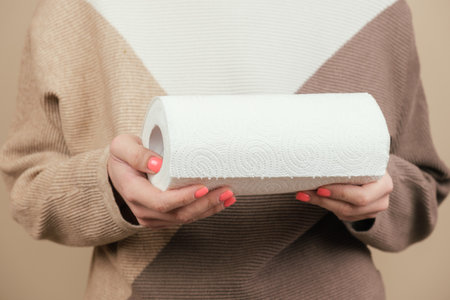 A woman holds a roll of paper kitchen towels in her hands. Disposable absorbent paper towels for kitchen use, wiping surfaces, wiping hands. Eco-friendly disposable household products.の写真素材