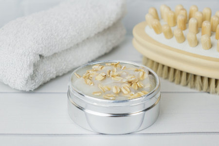Means for the production of natural scrub from body cream and oatmeal. Delicate cleansing of the skin of the body - wooden massage anti-cellulite brush, towel, jar of oatmeal purifying maskの写真素材