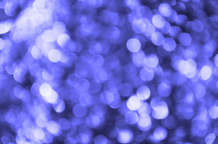 Abstract background with glowing blurred color Very Peri circles. Bokeh in colors of 2022. Glitter vintage lights background. Defocused. Festive new year and Christmas background with violet lightsの写真素材