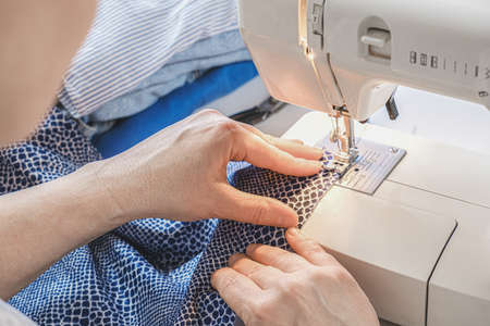 Seamstress makes a seam on an electric sewing machine. Close-up of hands. tailor workflow details.の写真素材