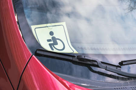 Disabled person driving sign on the windshield of a car. Identification symbol confirming the right of disabled car owners to benefitsの写真素材