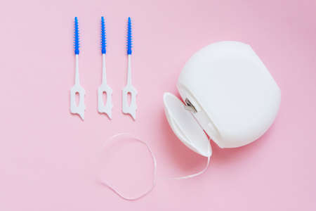 Oral Care: Dental Floss and brush for cleaning interdental spaces on a pink background. top view. Concept: dental services, oral hygiene, dental care.の写真素材