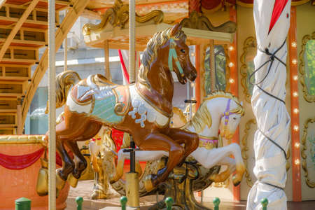 Children's vintage carousel with figures of horses. A working carousel without people. Colorful fair carousel on the square.の写真素材