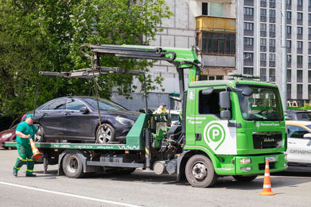 Tow truck is loading a car. Evacuation of parked cars that violate traffic rules. city traffic control service. Moscow, Russia - 06.01.2022のeditorial素材