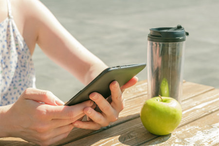 Close-up of hands with an electronic reader. Woman reads a book near the office during a work break....