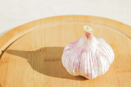 Head of fresh garlic on a wooden cutting board. Garlic is one of the most popular spices in the world. Farm garlic is selected slices of a perennial plant from the onion family.の写真素材
