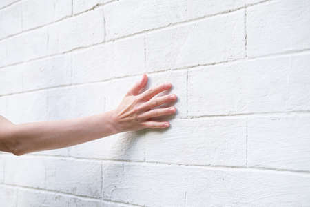 Woman's hand on the background of a white brick wall. A woman touches the old wall of the monastery.の写真素材