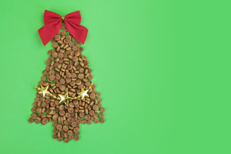 Dry dog food Christmas tree with red bow on top and garland on green background. Christmas pet supplies concept, New year and Christmas celebration. Top view, space to insert text.の写真素材
