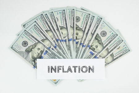 Inscription inflation on the background of scattered dollar bills on a white background. The concept of economic inflation, depreciation of savings.の写真素材