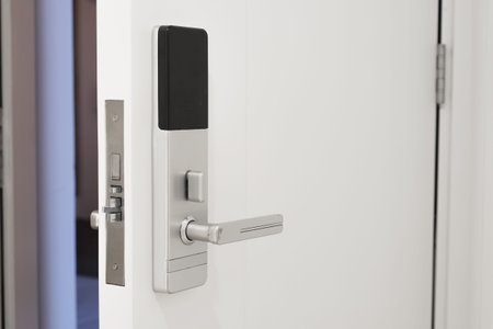 Slightly open white door to the hotel room with a Electronic magnetic lock. Electronic hotel lock...