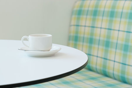 White coffee cup on a saucer on a round empty table. A cup of cappuccino on a table in a cafe. Used dishes left on the table in a coffee shop.の写真素材