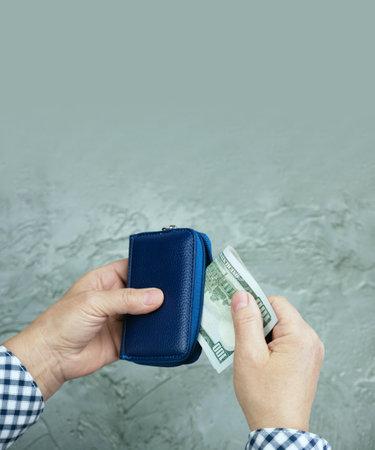 Woman puts dollar bills in a small travel wallet. Use of cash. The concept of a budget in travel, financial security.の写真素材