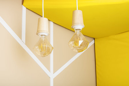 Unusual faceted incandescent lamps in wooden sockets on a white wire. Room design, lighting fixtures. interior details.の写真素材