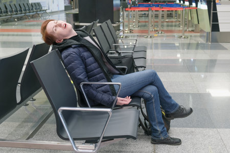 Woman sleeps with her mouth open in the departure area of an international airport. The flight passenger overslept the departure time.の写真素材
