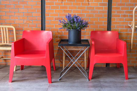 Two red plastic armchairs and decorative bouquet of artificial lavender flowers in a large black wide vase on a coffee table. Interior decoration with artificial flowers and plants. interior details.の写真素材