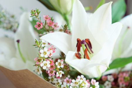 Close-up of a white lily surrounded by small Chamelaucium flowers. A delicate spring bouquet, art of floristryの写真素材