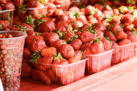 Counter with fresh ripe strawberries in plastic containers. Seasonal sale of berries. Retailの写真素材