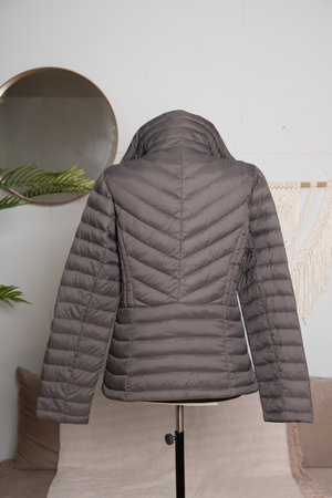 Short women's thin down jacket with a metal zipper on a tailor's mannequin. Demonstration of women's demi-season clothing for sale. Back viewの写真素材