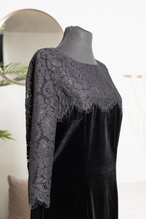 Black velvet dress with a lace top and three-quarter sleeves on a tailor's mannequin. Side view. Demonstration of clothes in an online store.の写真素材