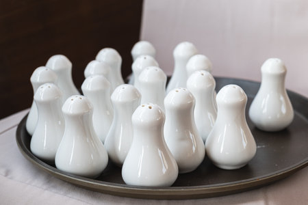 There are a lot of white ceramic salt shakers on the tray. Dishes in restaurants and cafes.の写真素材
