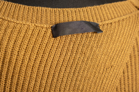 Silk label on the back of the collar of a knitted sweater. Clothes on a tailor's mannequin
