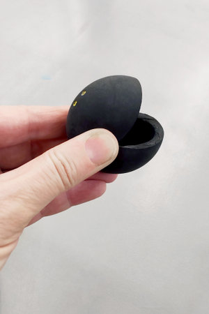 Double yellow dot Burst squash ball in the player's hand. Ball for a professional squash game on the background of the court.の写真素材