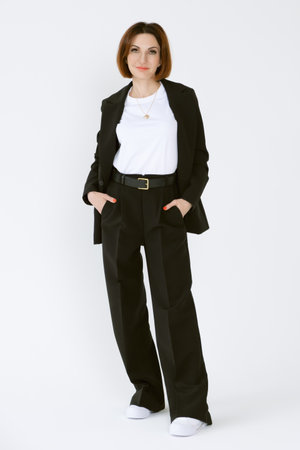 Portrait of a confident business woman in a black pantsuit and a white blouse on a white background. Full-length portrait of a middle-aged woman in black trousersの写真素材