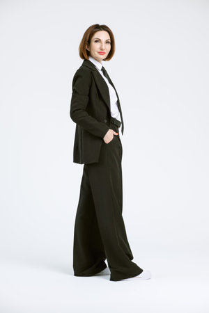 Portrait of a confident business woman in a black pantsuit and a white blouse on a white background. Full-length portrait of a middle-aged woman in black trousersの写真素材
