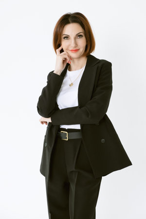 Portrait of a confident business woman in a black pantsuit and a white blouse on a white background. Portrait of a middle-aged woman in black trousersの写真素材